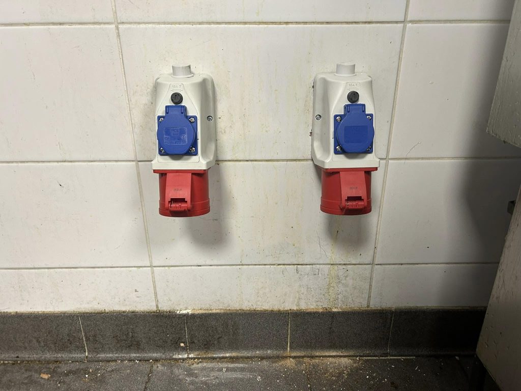 Two heavy-duty industrial sockets installed on a tiled wall—each unit featuring a blue 16A and red 32A outlet, professionally mounted for safe and efficient power distribution.