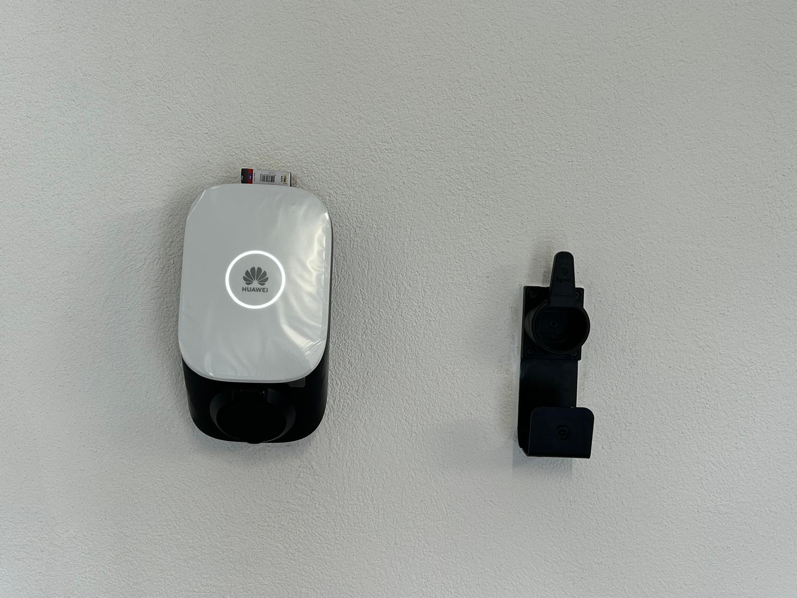 Huawei EV Charger installed on a white wall next to a cable holder.